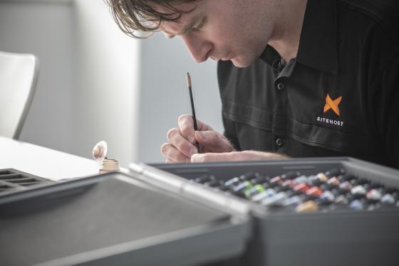 A SiteHost team member painting figurines.