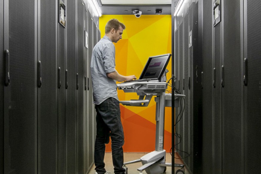 A SiteHost team member working on a connected laptop in the data centre.