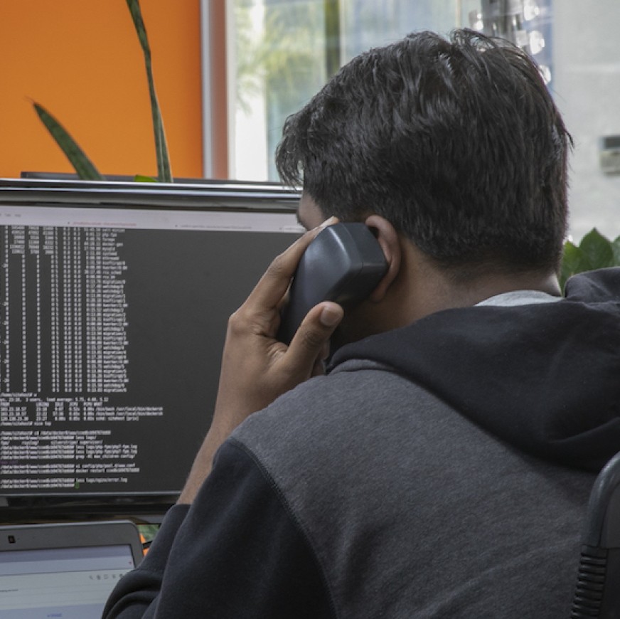 A SiteHost support team member talking with a customer and analysing code.